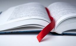 new open book on a gray table with a red ribbon bookmark